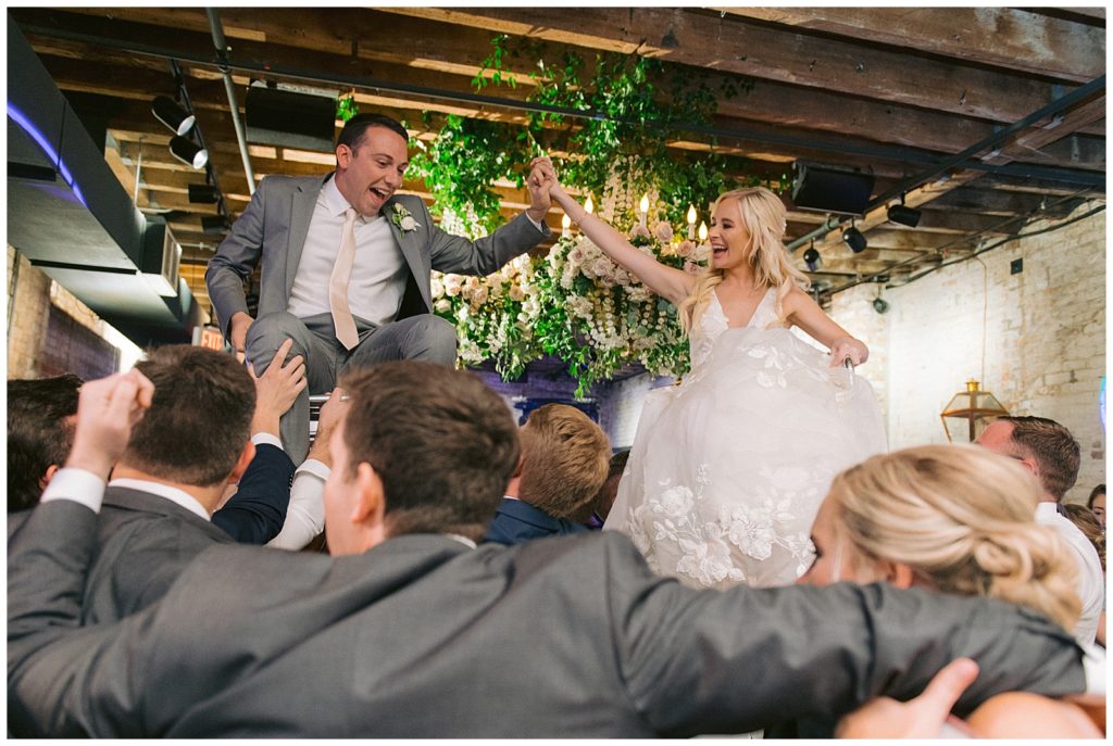 Bride and Groom laugh as they are thrown in air during hora dance at their reception at the Chicory in New Orleans