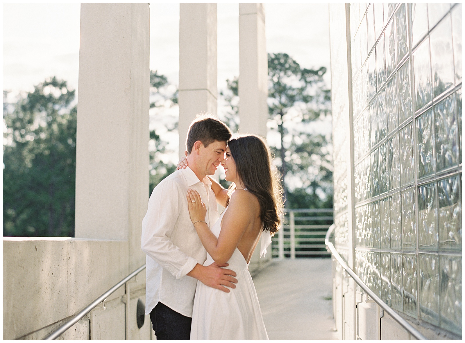 Couple wearing white poses outside New Orleans Museum of Art during sunset