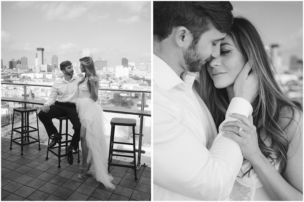 A couple wearing white and black attire sits facing each other at Hot Tin rooftop bar at the Pontchartrain Hotel for their New Orleans engagement session.